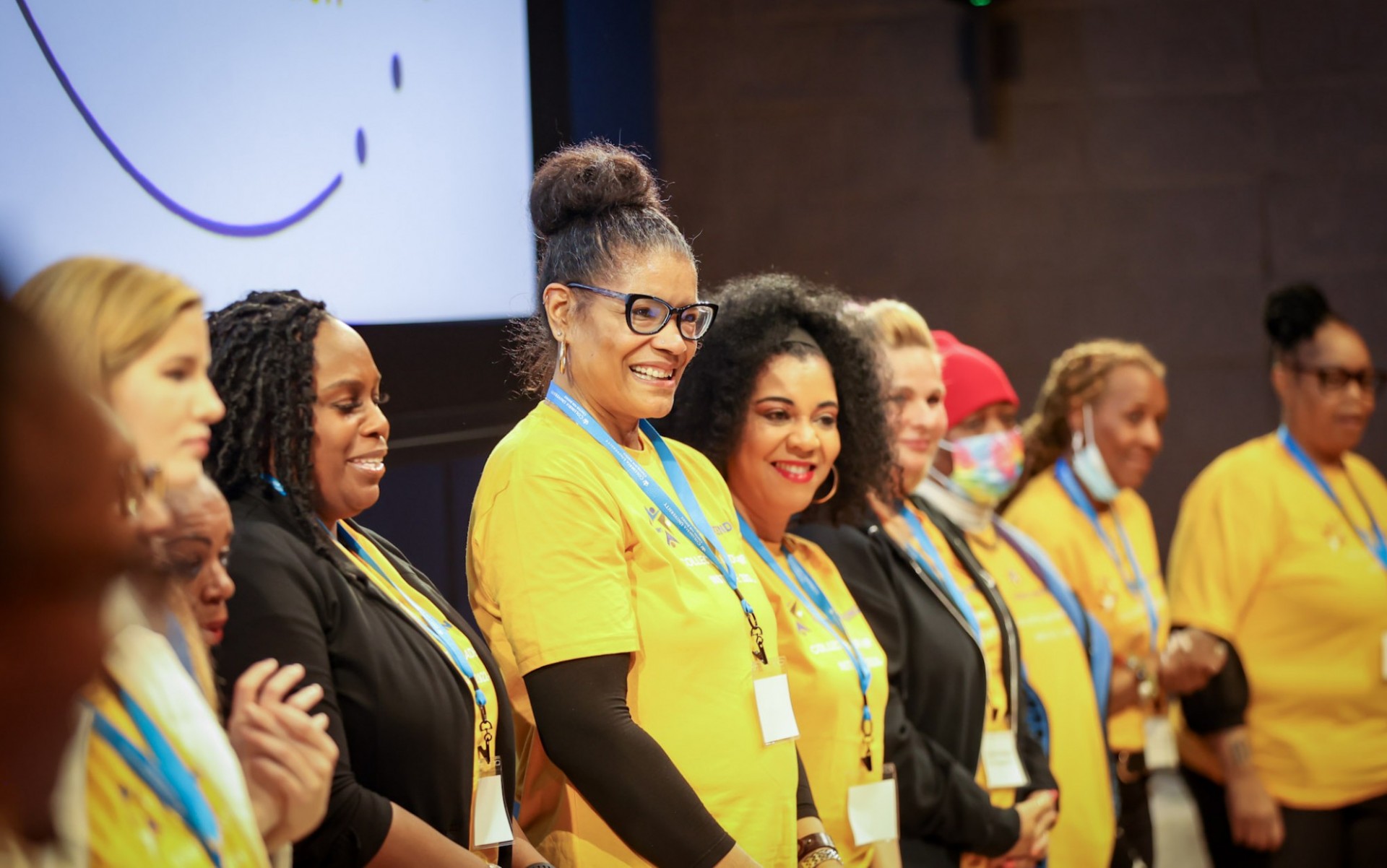 Collective Leadership member standing in a line in yellow shirts on stage