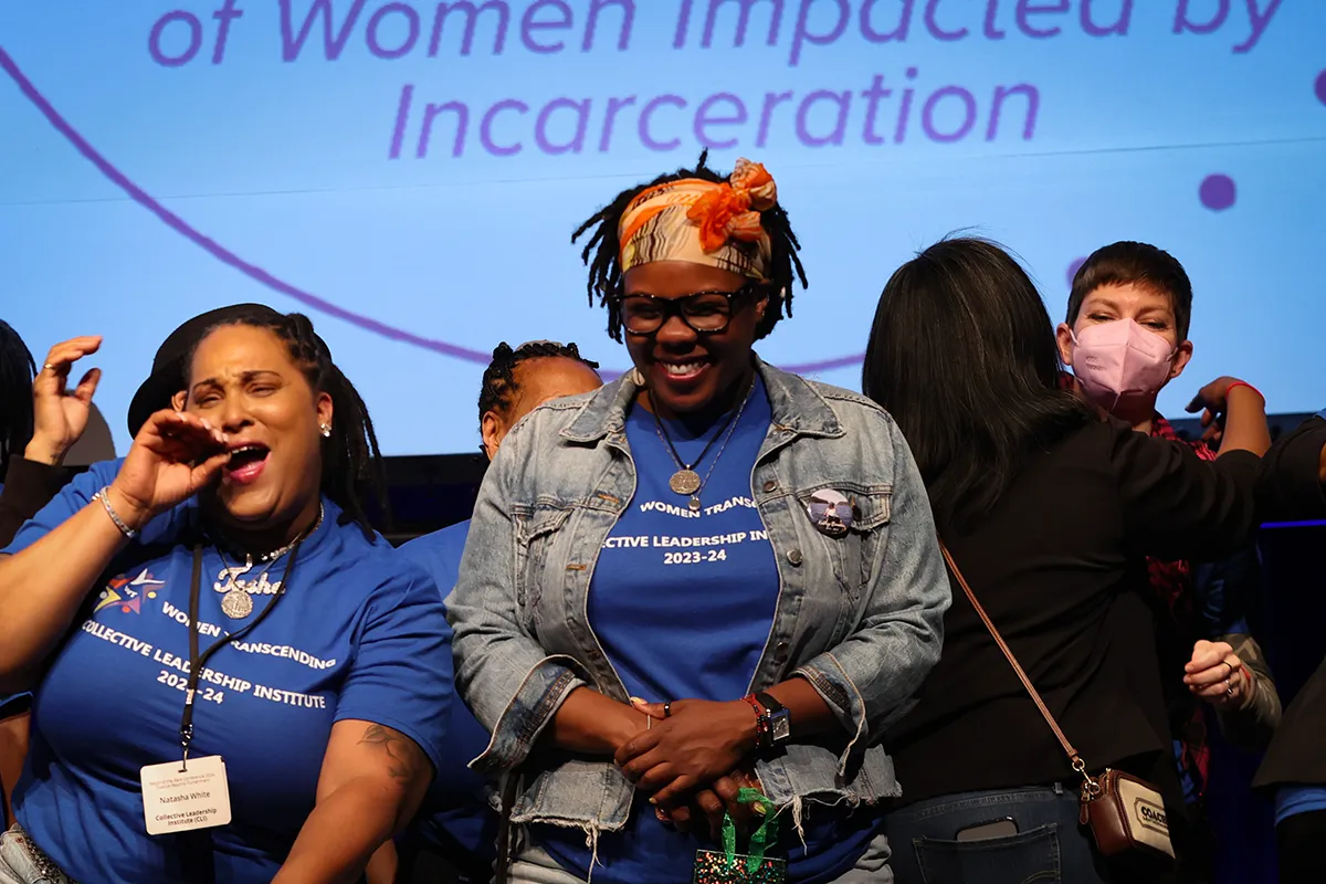 Women in matching blue shirts on stage smiling