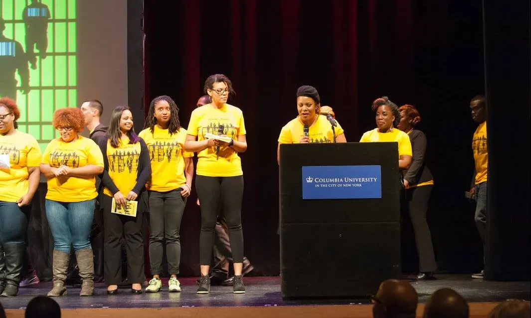 A group of people in yellow shirts standing on a stage behind a podium