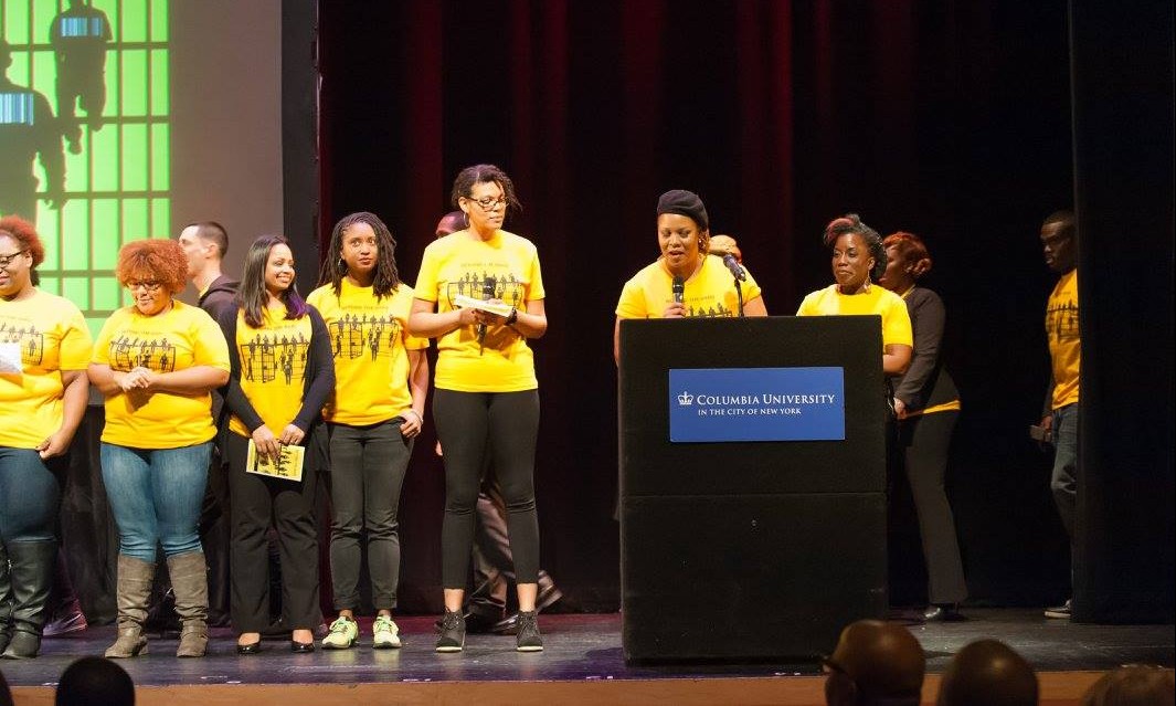 A group of people in yellow shirts standing on a stage behind a podium