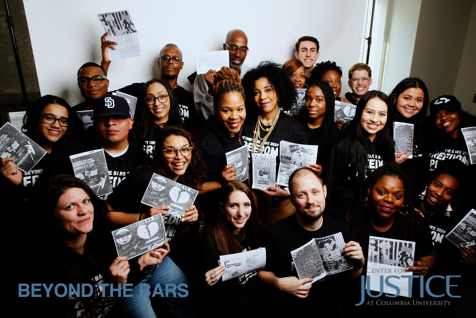 Group photo of people in black shirts holding up a piece of paper