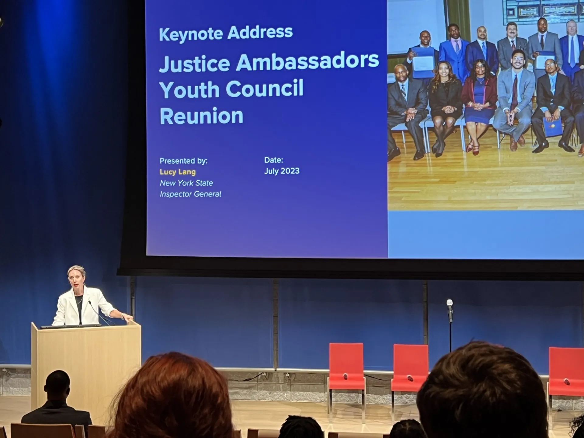 Photo of Lucy Lang at a podium with the screen behind her that says Keynote Address Justice Ambassadors Youth Council