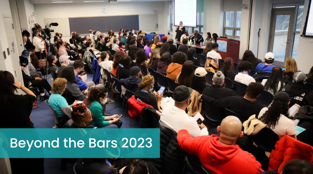 Large group of people in a classroom listening to a panel 