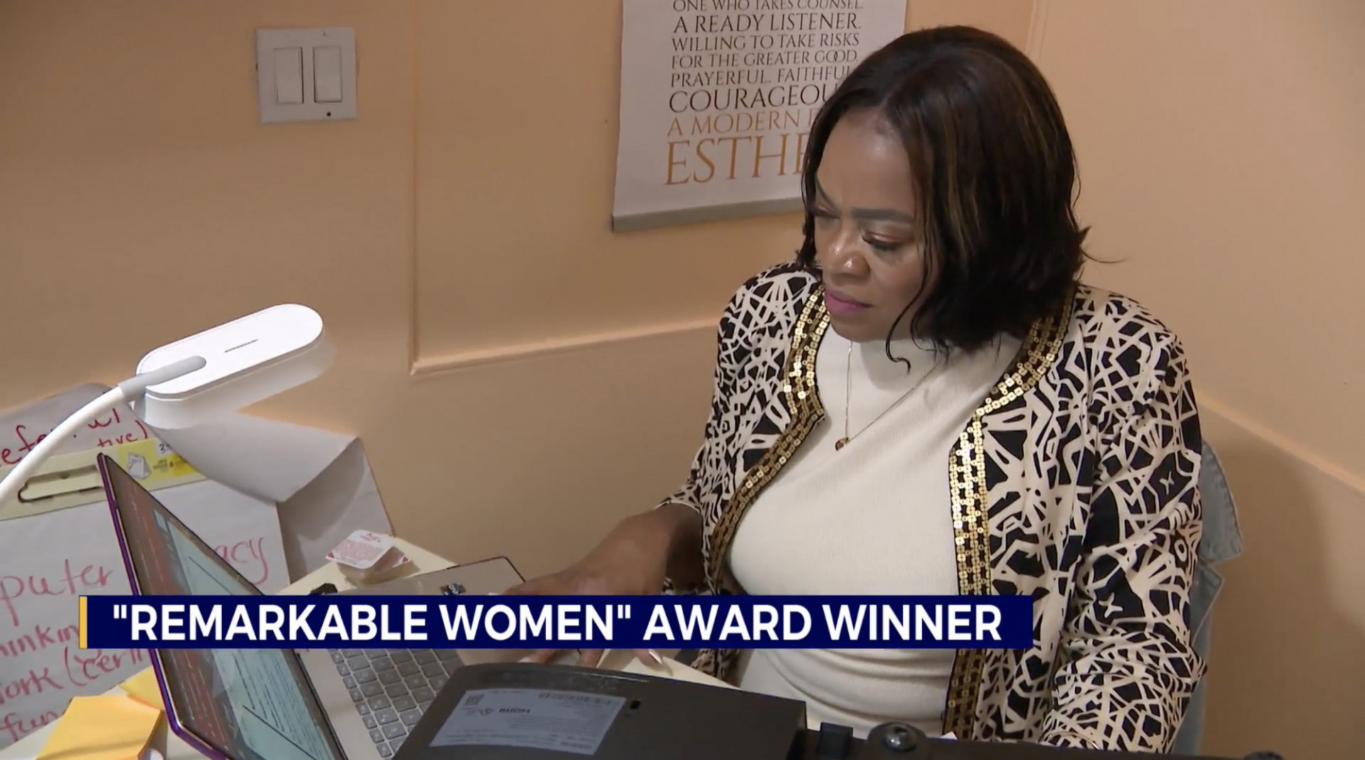 Photo of a woman sitting at a desk with the text "Remarkable Woman Award Winner"
