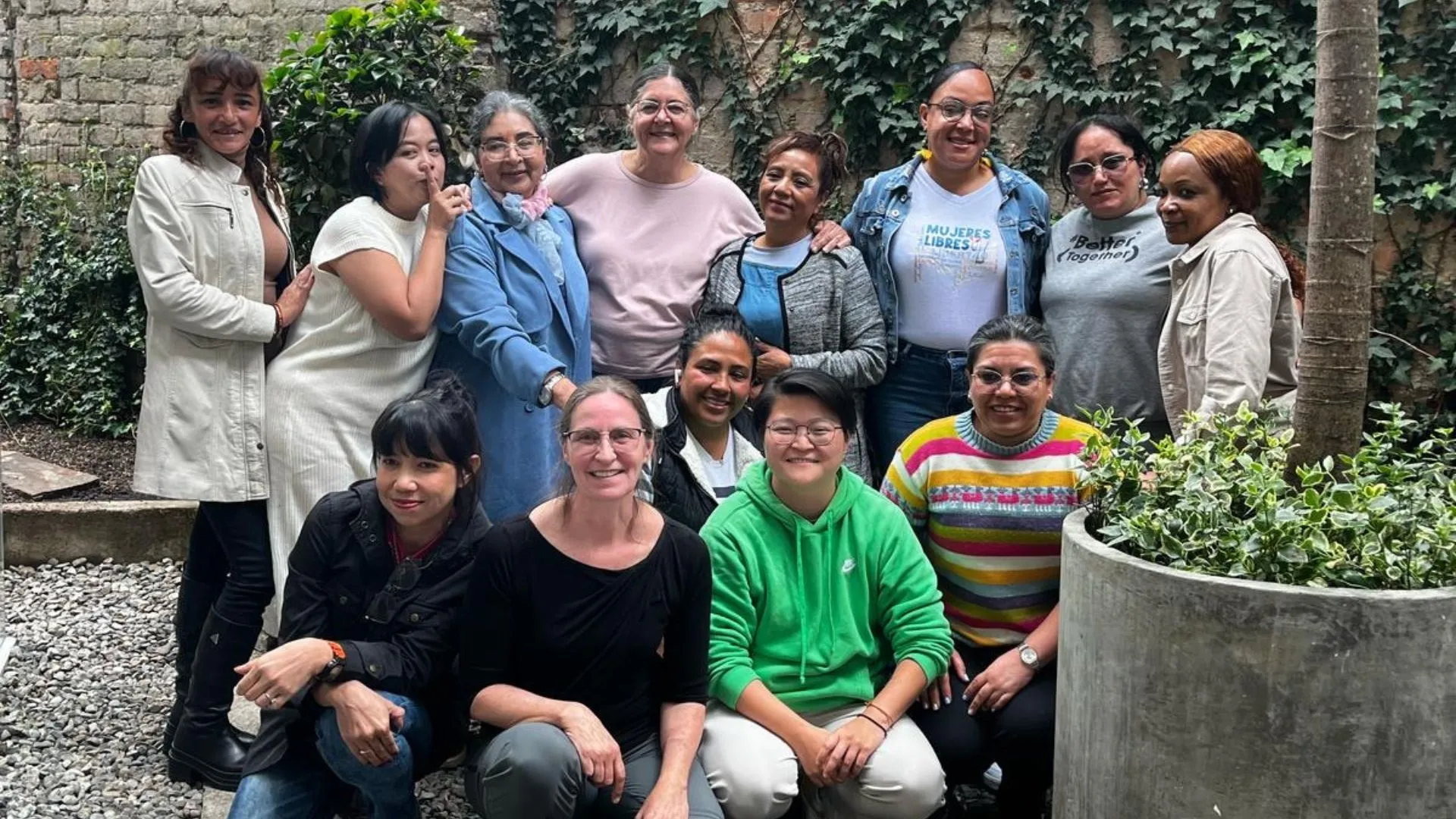 Group photo of women in front of a brick wall with greenery