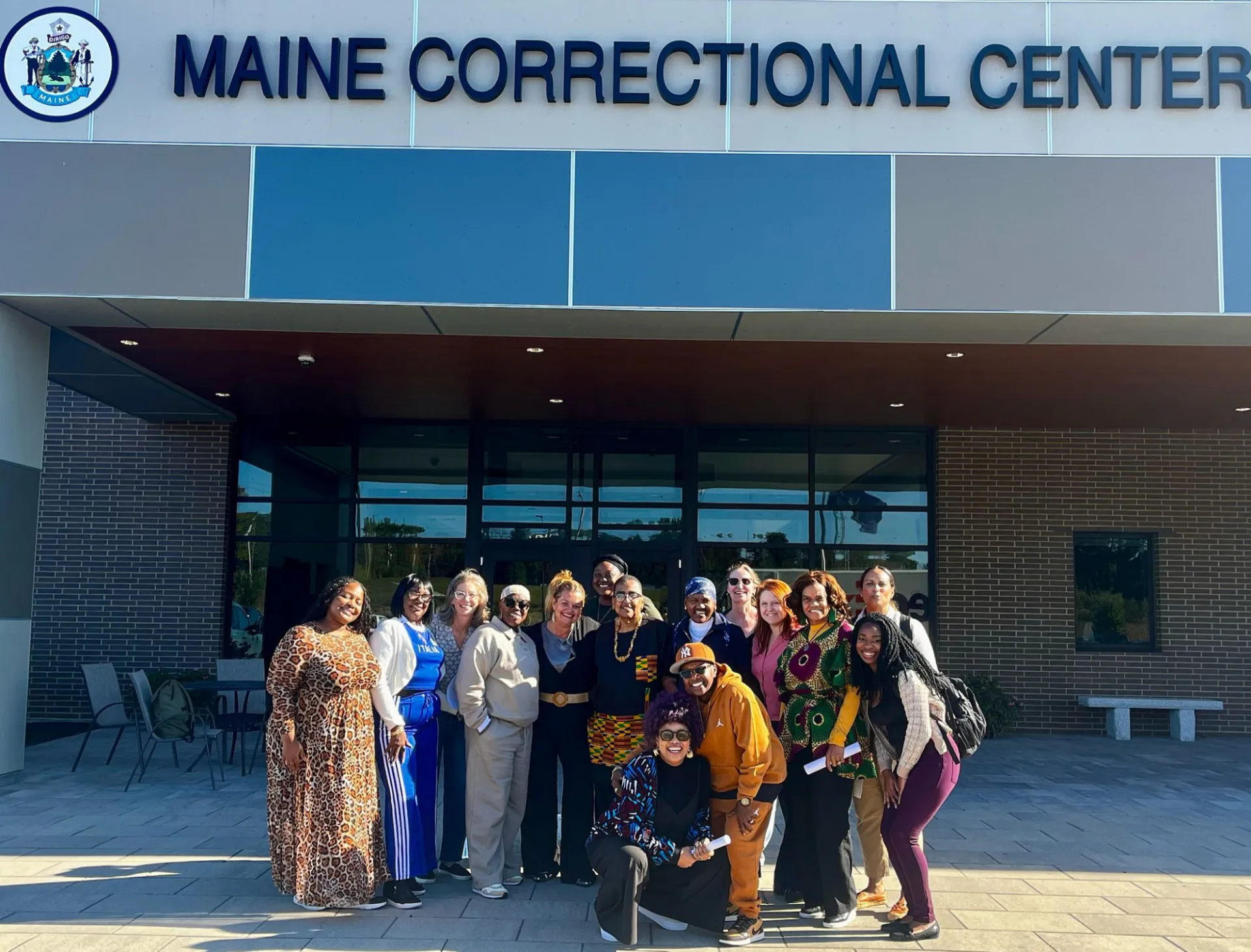 A group of women in front of a building that says "Maine Correctional Center"