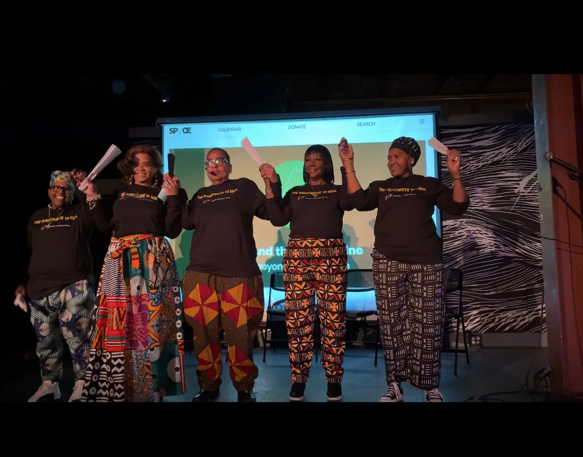 Women holding hands on a stage to take a bow