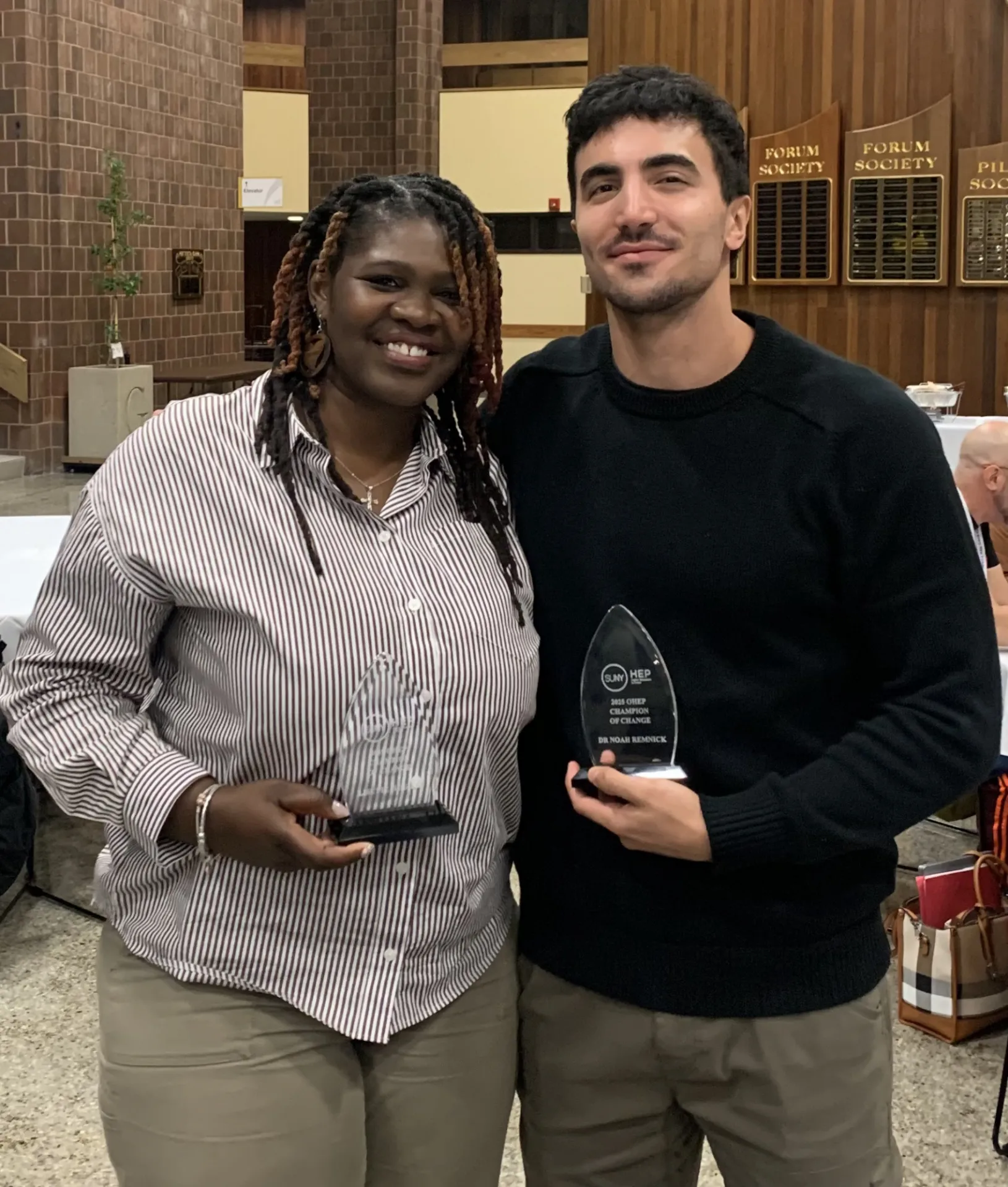 Two people posing for a picture holding awards 