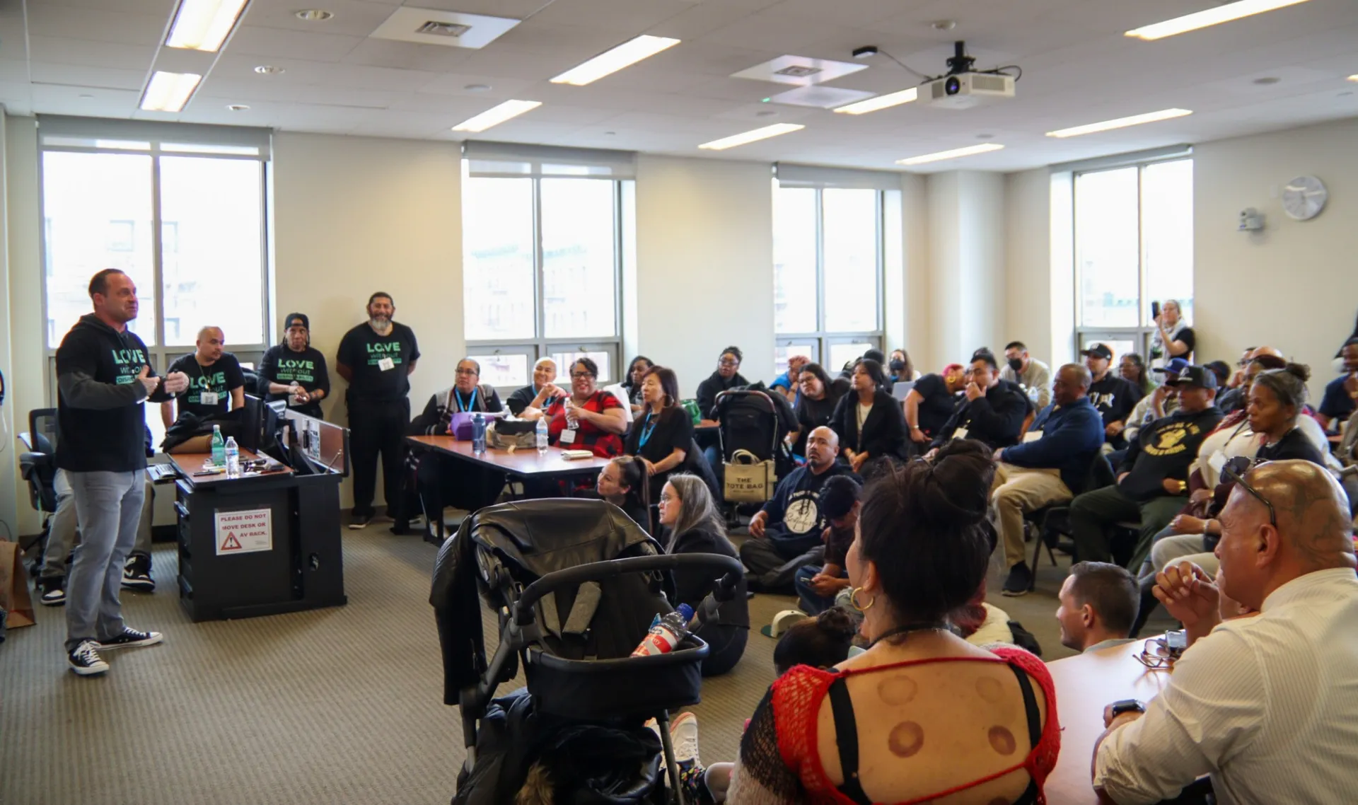 Classroom packed with people listening to a workshop leader 