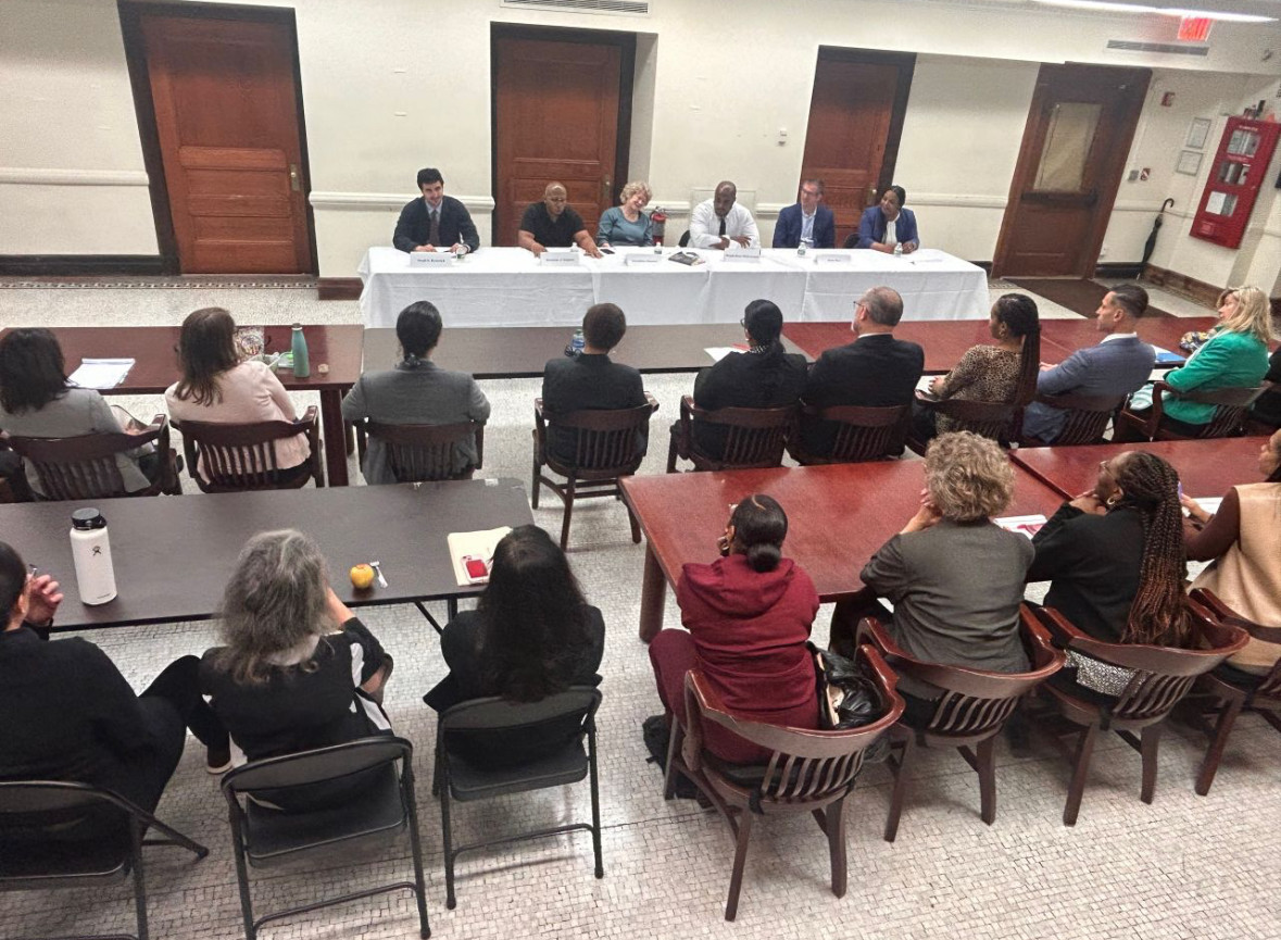 A group of people at tables facing a table of panelists 
