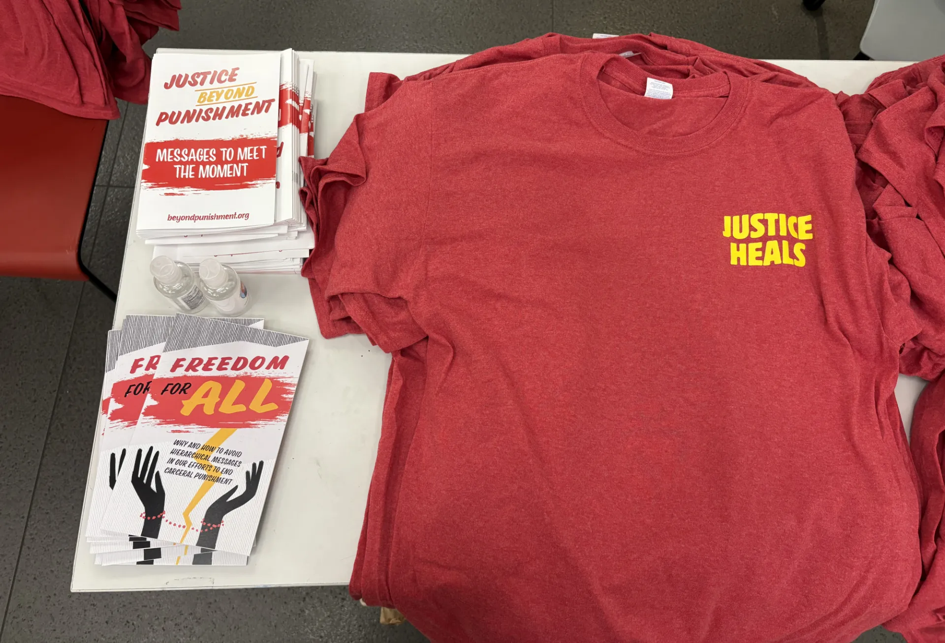 A photo of a read shirt that says "Justice Heals" and two resources, one that says "Freedom for All" and the other that says "Justice Beyond Punishment: Messages to Meet the Moment"