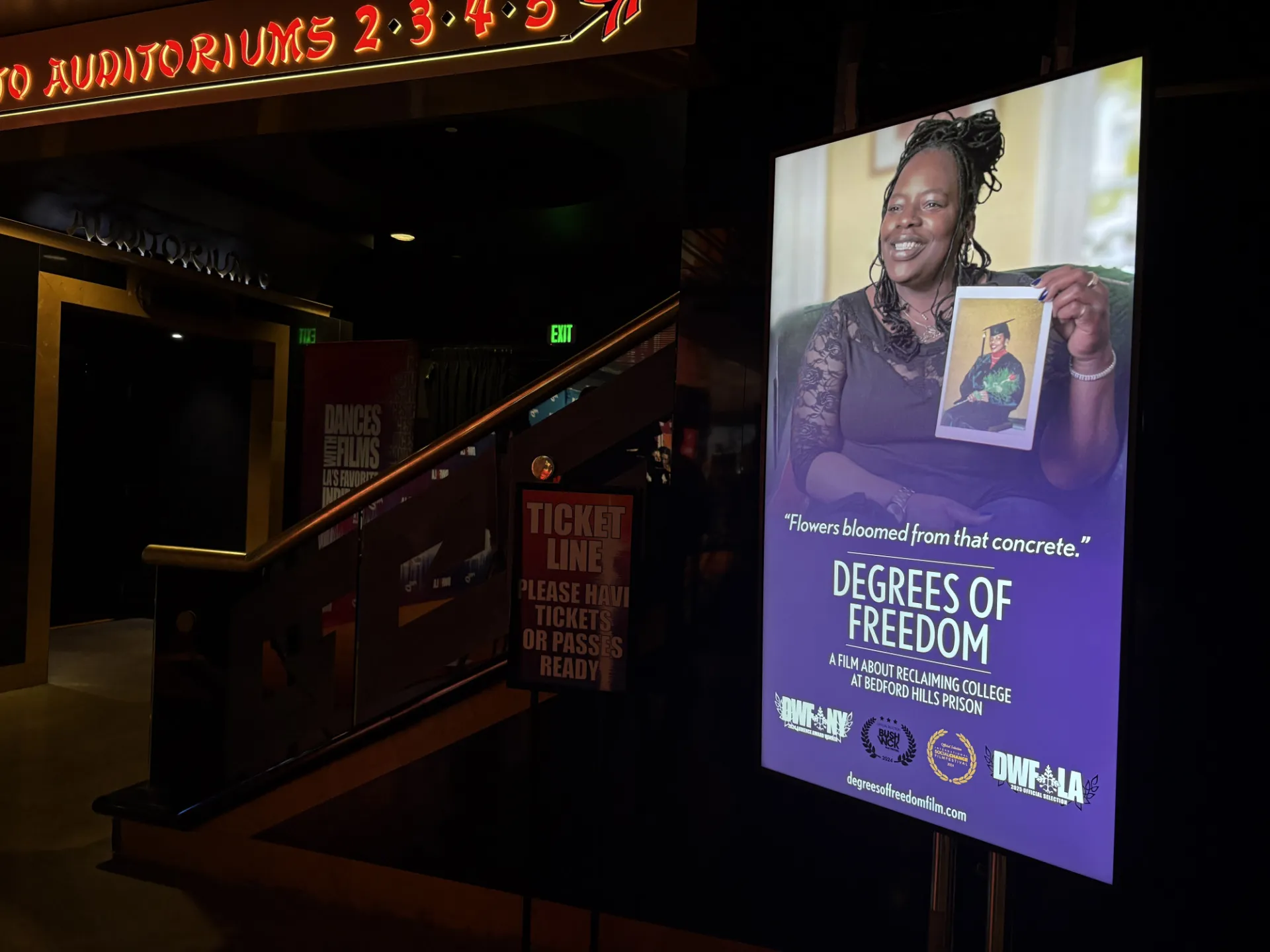 A screen that shows a movie poster that says Degrees of Freedom and has a photo of a Black woman smiling holding up a picture or herself in a cap and gown