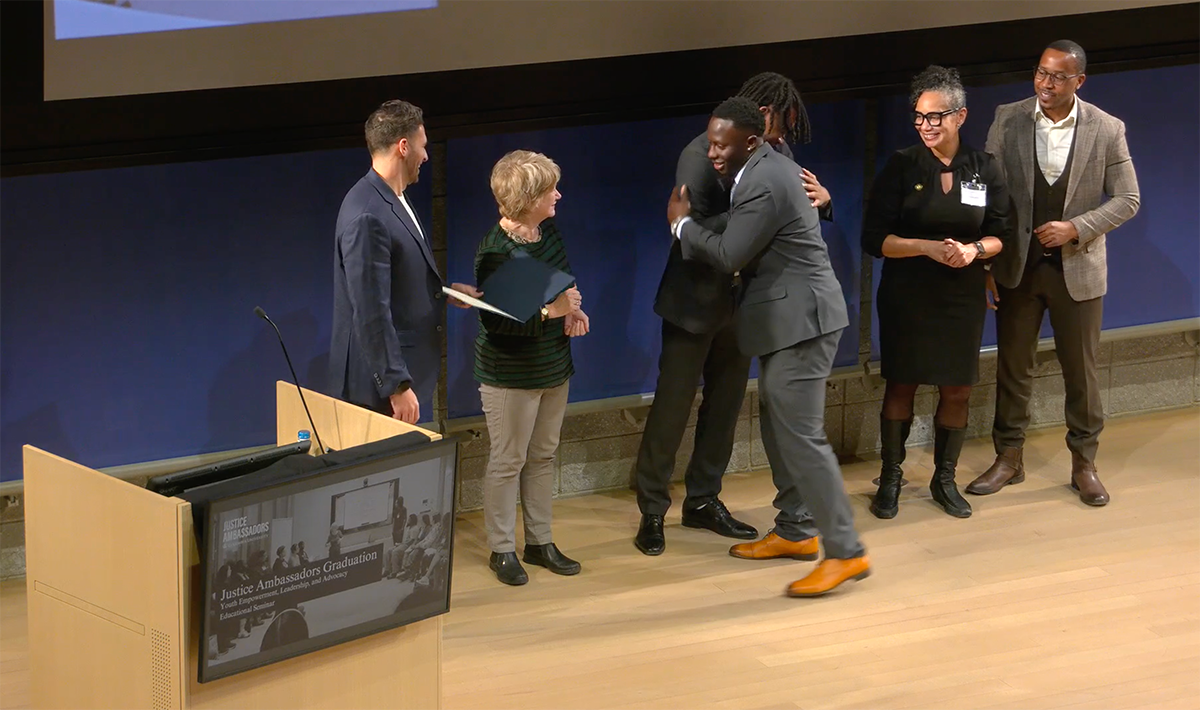 A line of people handing a certificate to a program graduate and congratulating him