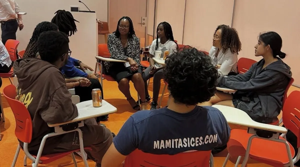 A group of people sitting in a circle at desks, talking