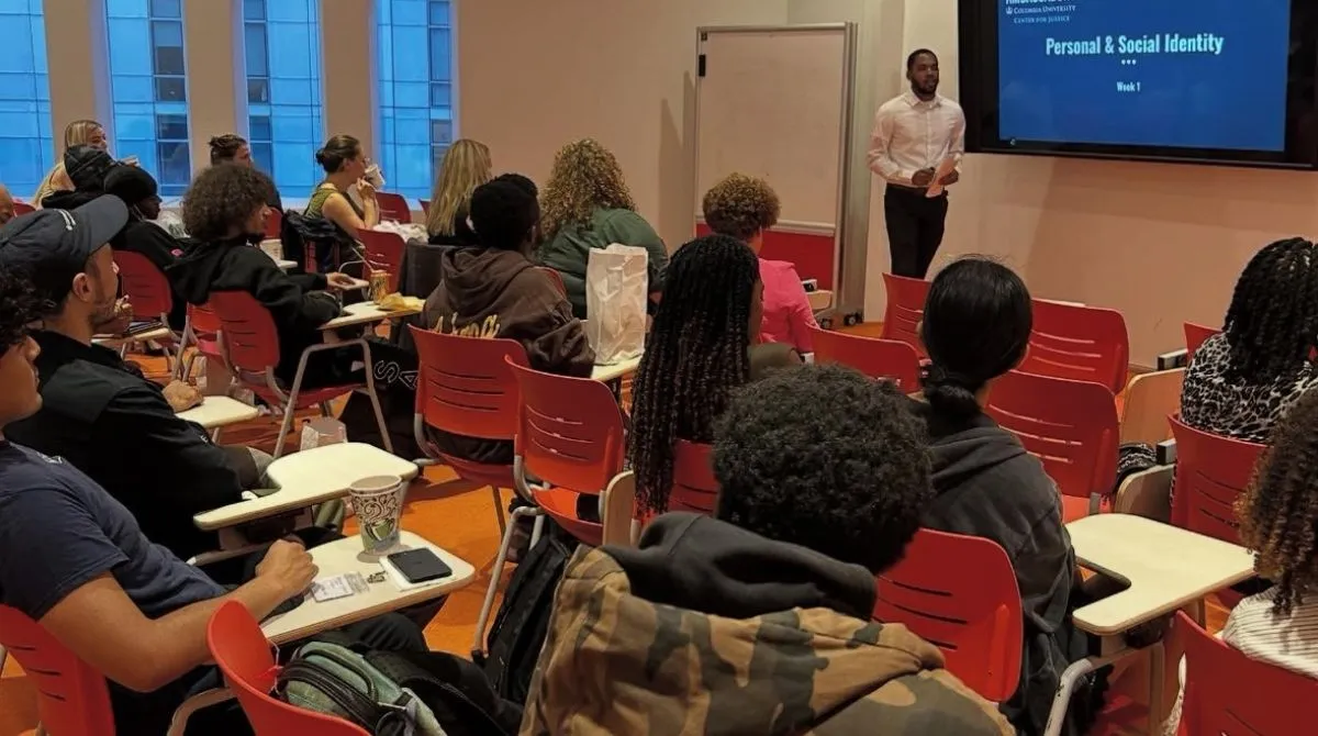 A group of people in a classroom looking at a screen with a presenter in the front
