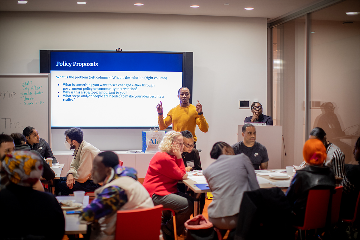 Man standing in front of classroom presenting policy proposal