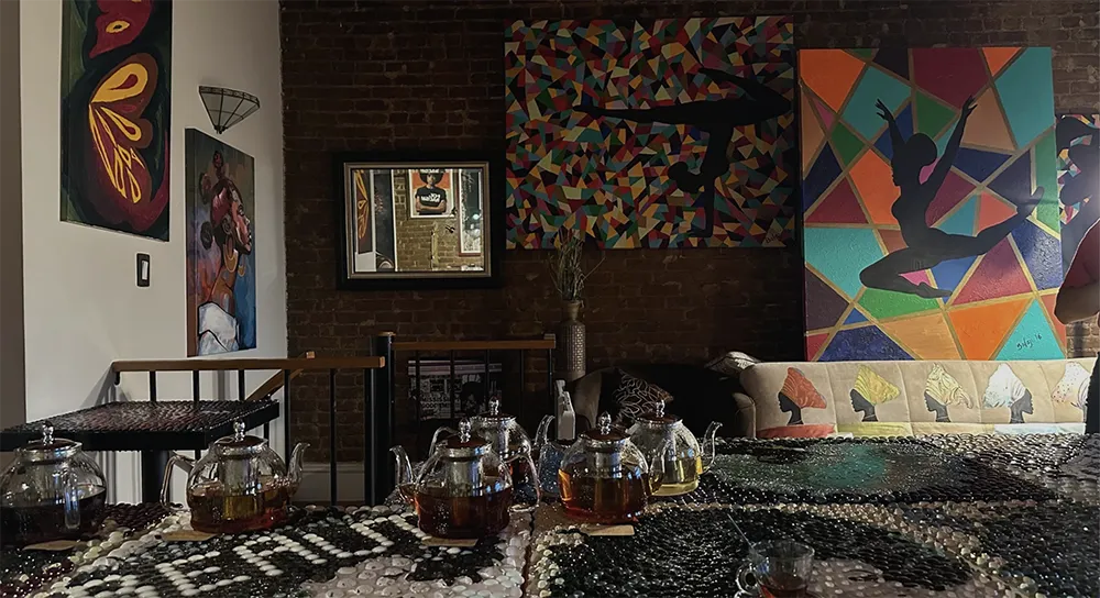 A photo of an art gallery with colorful art on the wall and a table with tea in the front