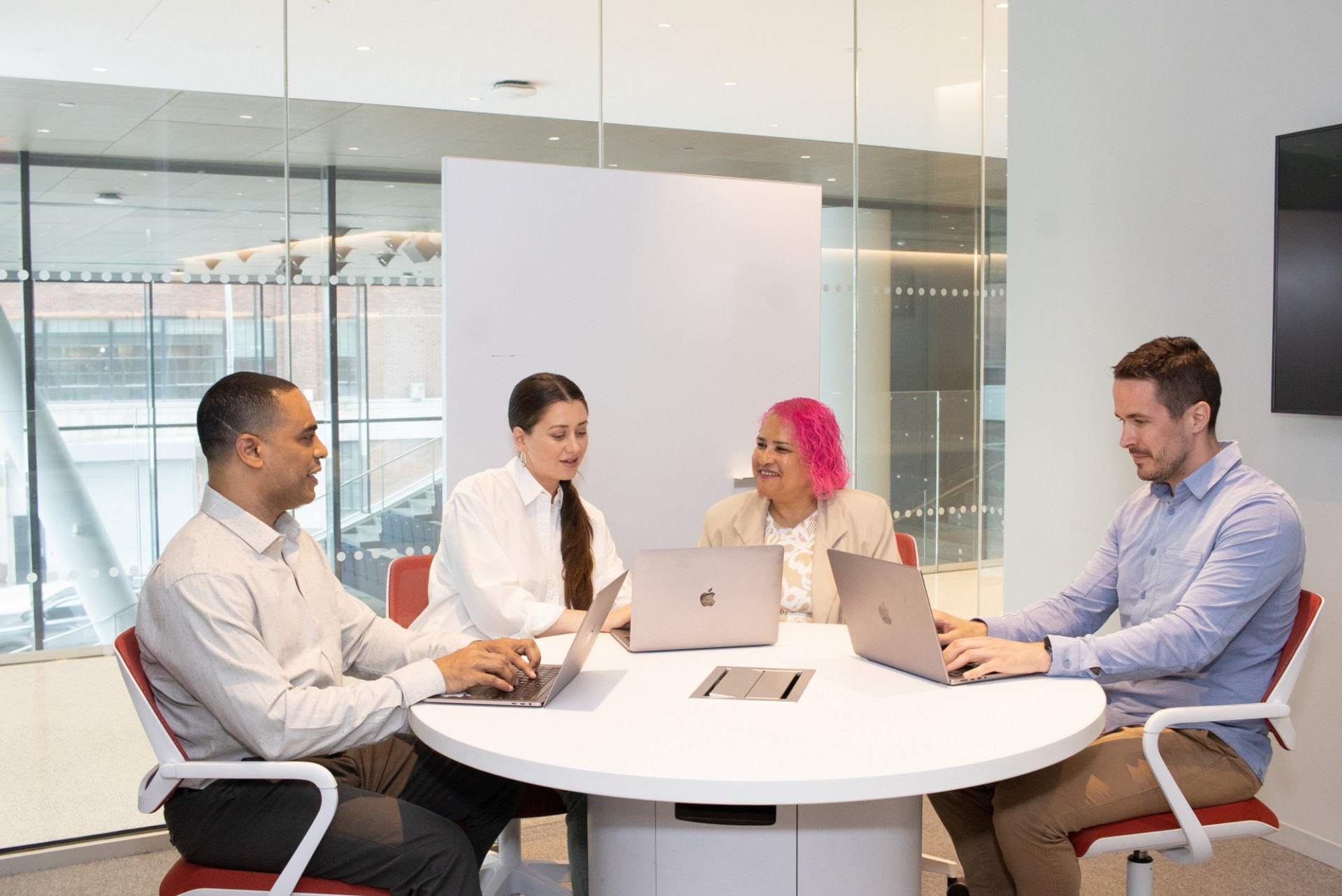 Four people sitting around table on laptops