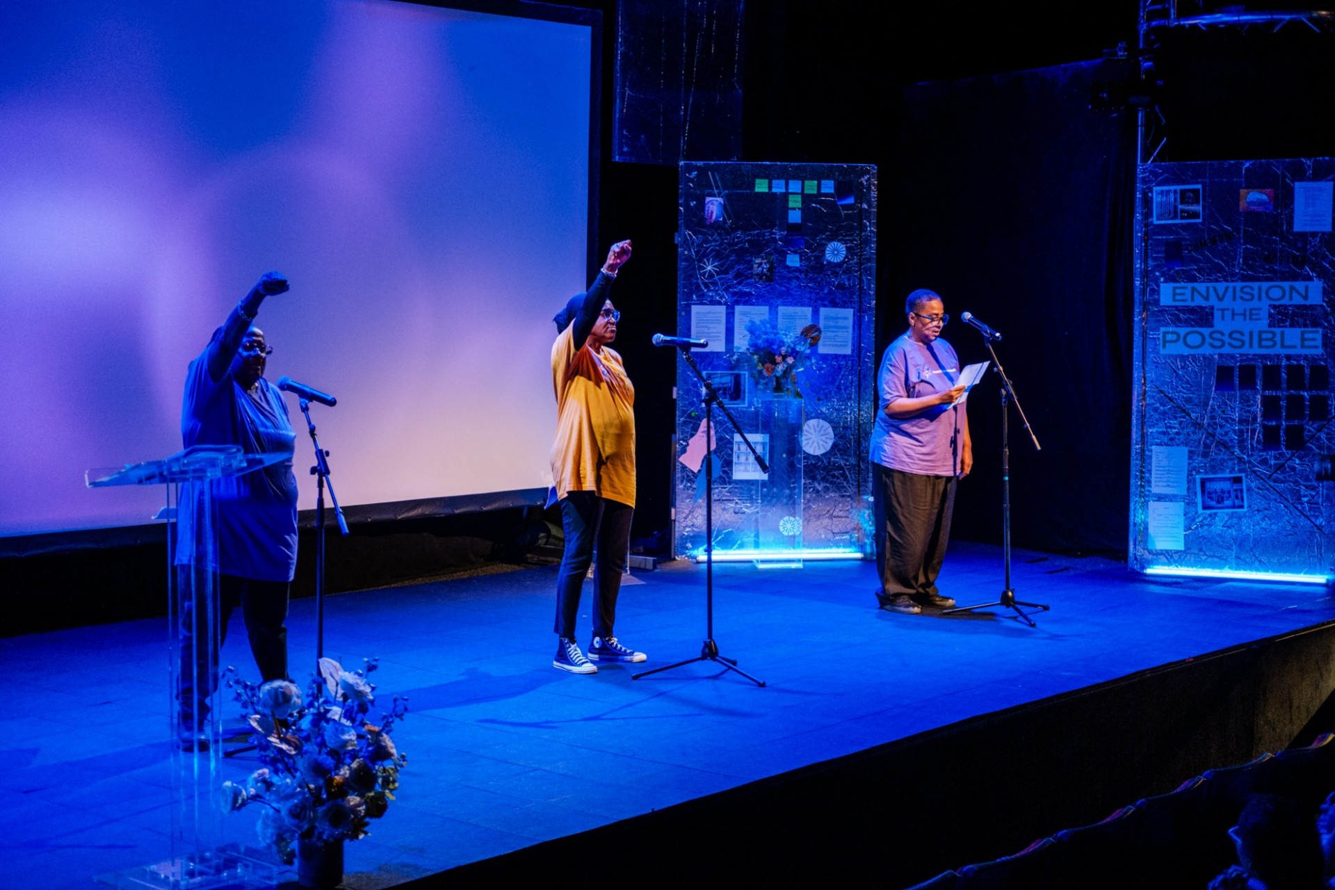 Three women on stage performing a spoken word