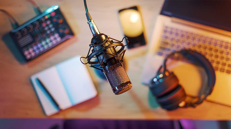 A mic hovering over a desk with a laptop and podcast equipment