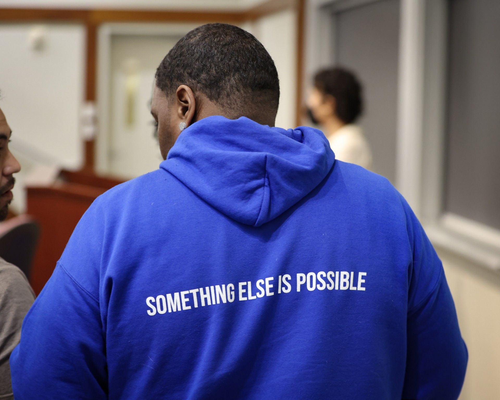The back of a blue sweatshirt that says "something else is possible"