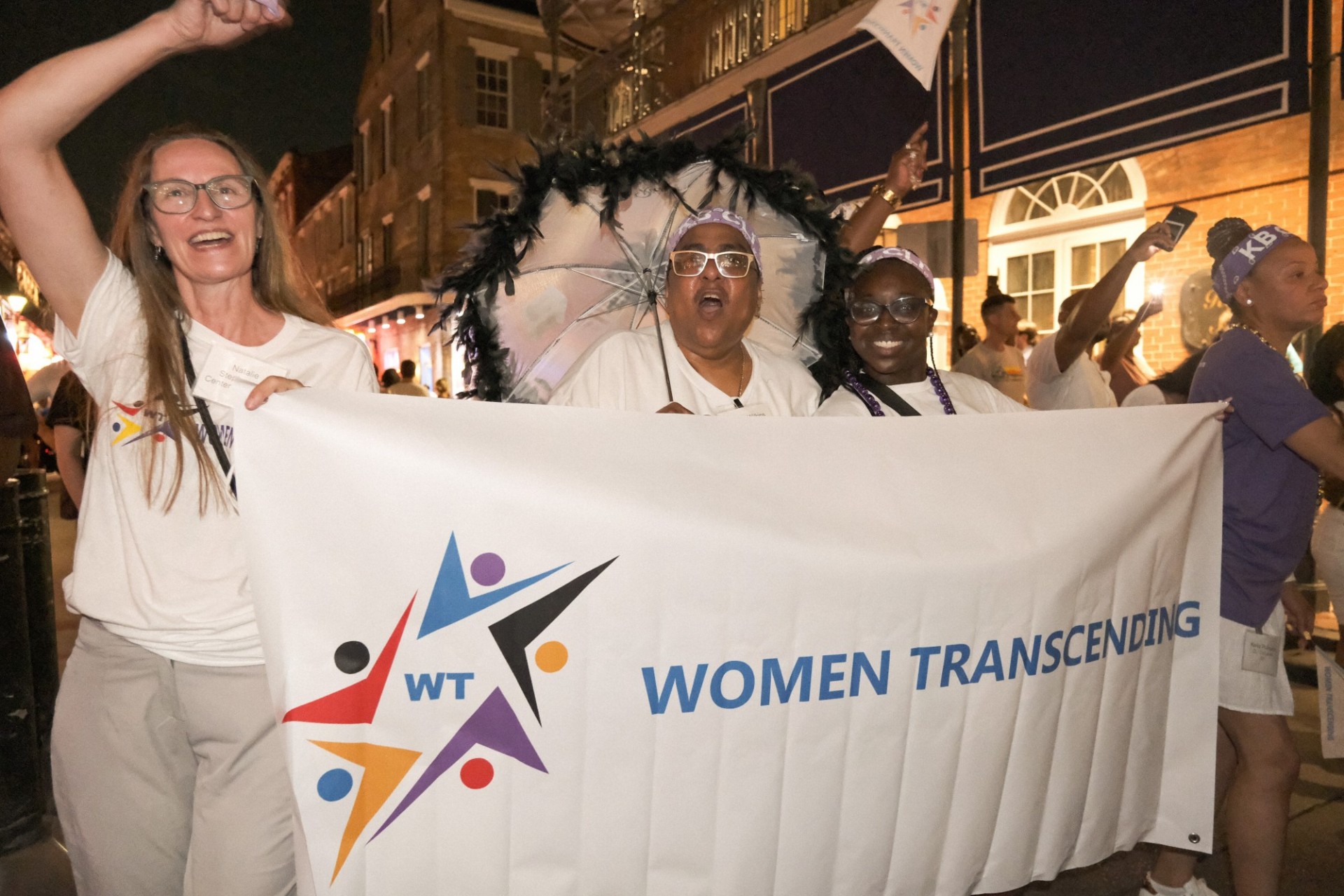 CfJ Staff holding a Women Transcending Banner down Bourbon Street in New Orleans