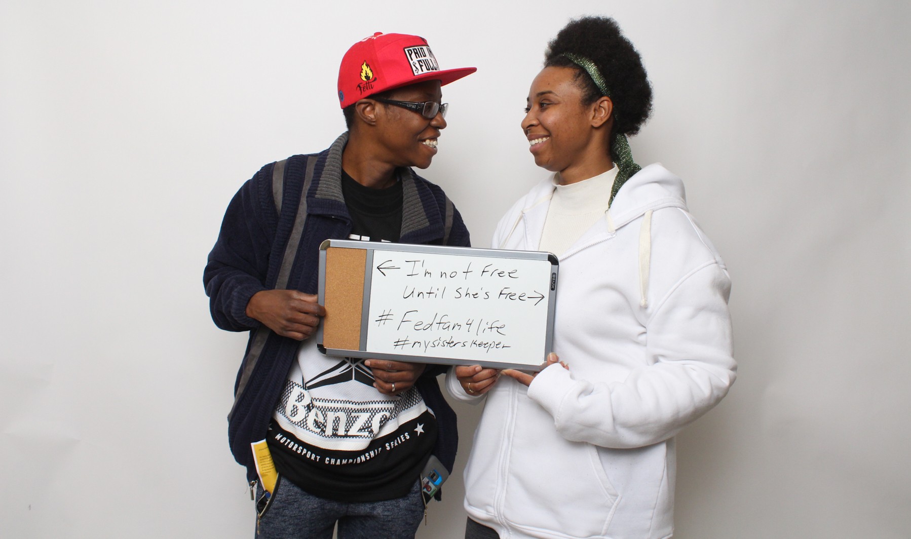 Beyond the Bars participants holding sign that says "I'm not free until she's free"