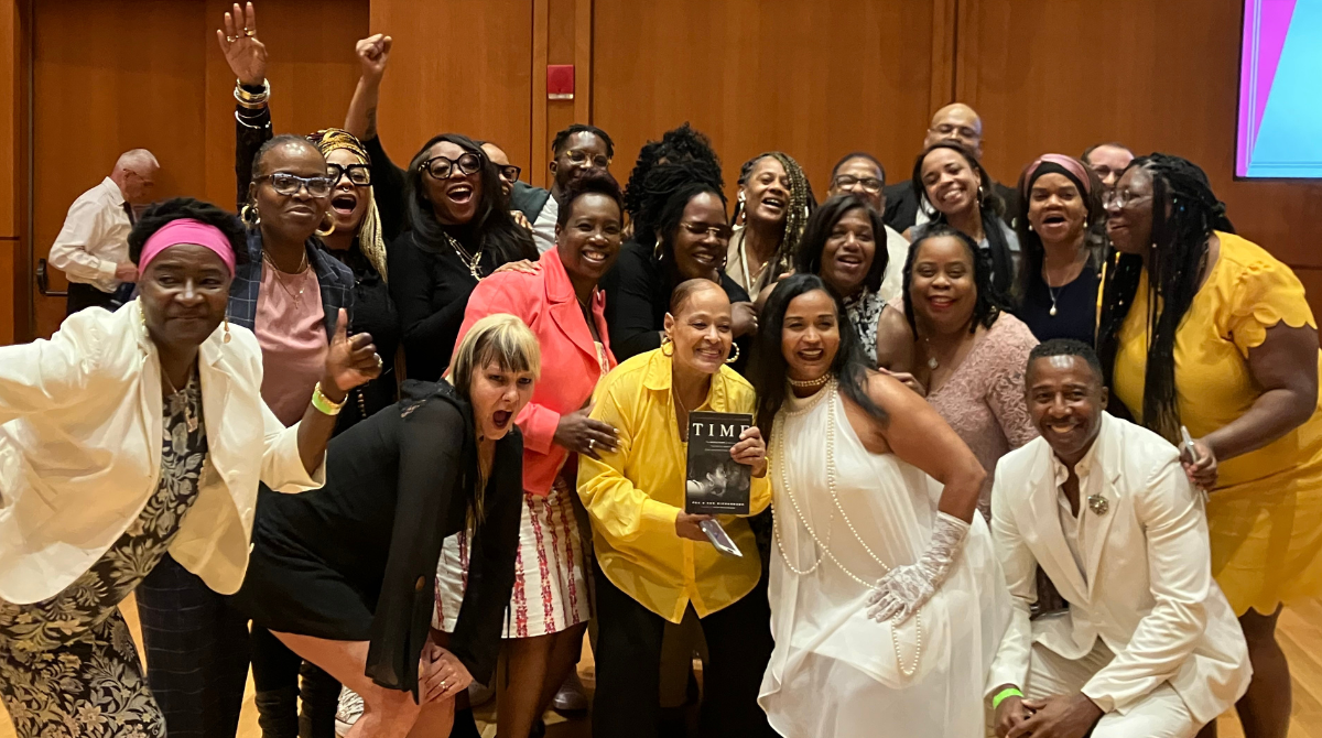 Group of mostly women smiling with fists in the air 