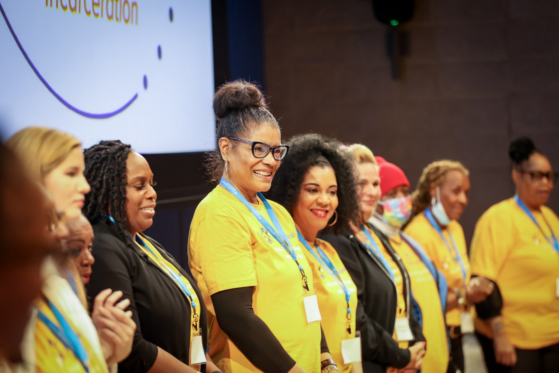 A row of women standing and smiling wearing yellow shirts