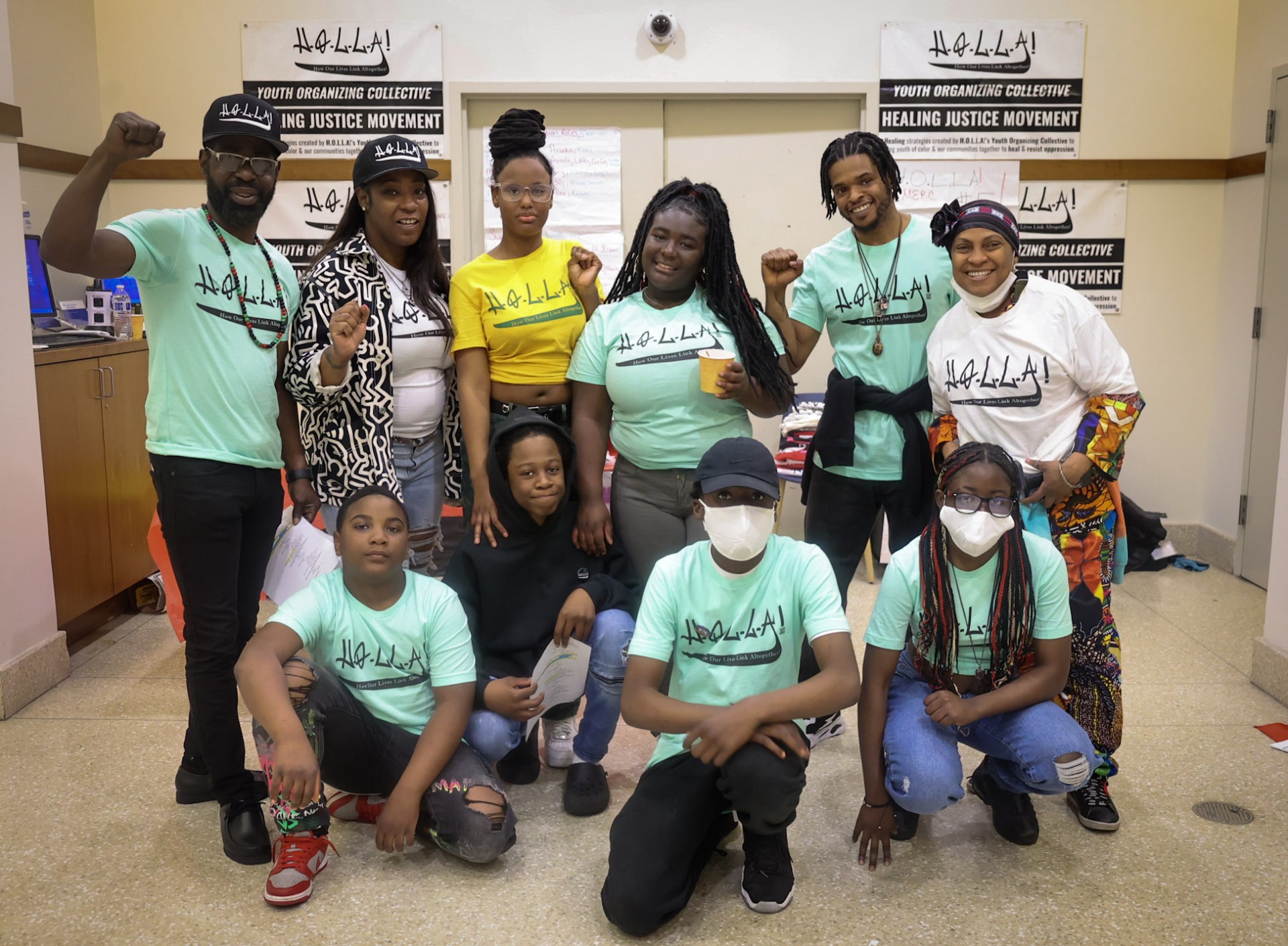 A group photo of young people smiling and putting their fists in the air with H.O.L.L.A. t-shirts on