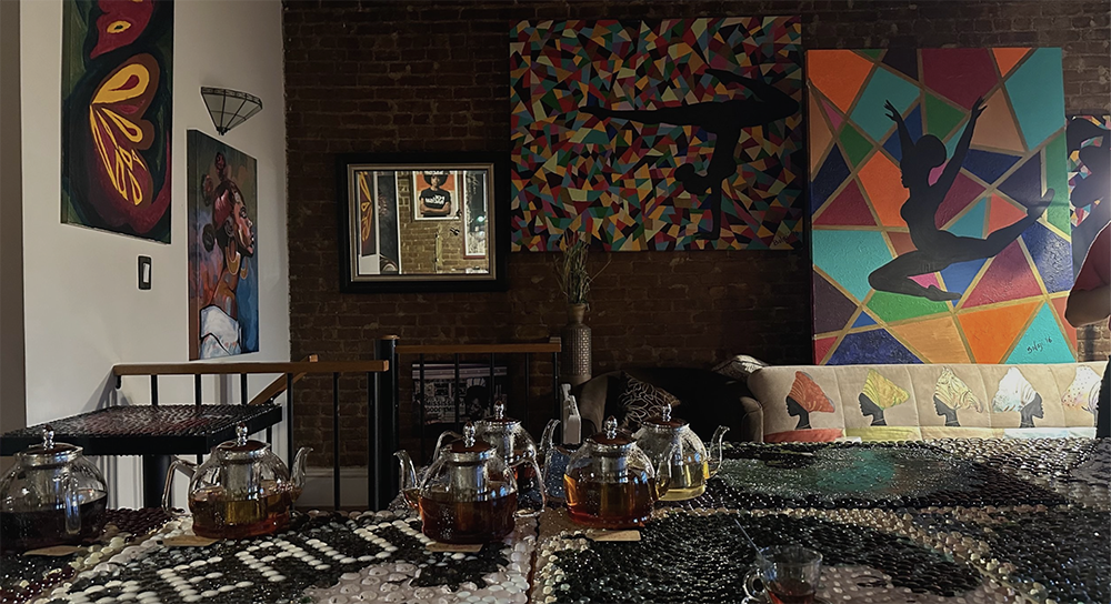 A photo of an art gallery with colorful art on the wall and a table with tea in the front