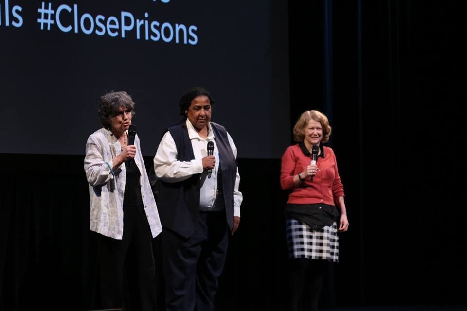 Kathy Boudin, Cheryl Wilkins, and Geraldine Downey appear standing onstage holding microphones.
