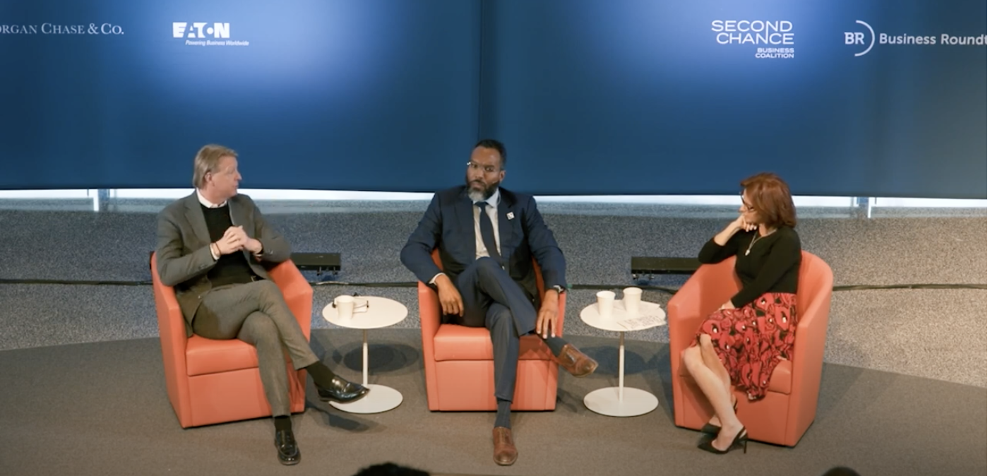 Three panelists sitting in red chairs 