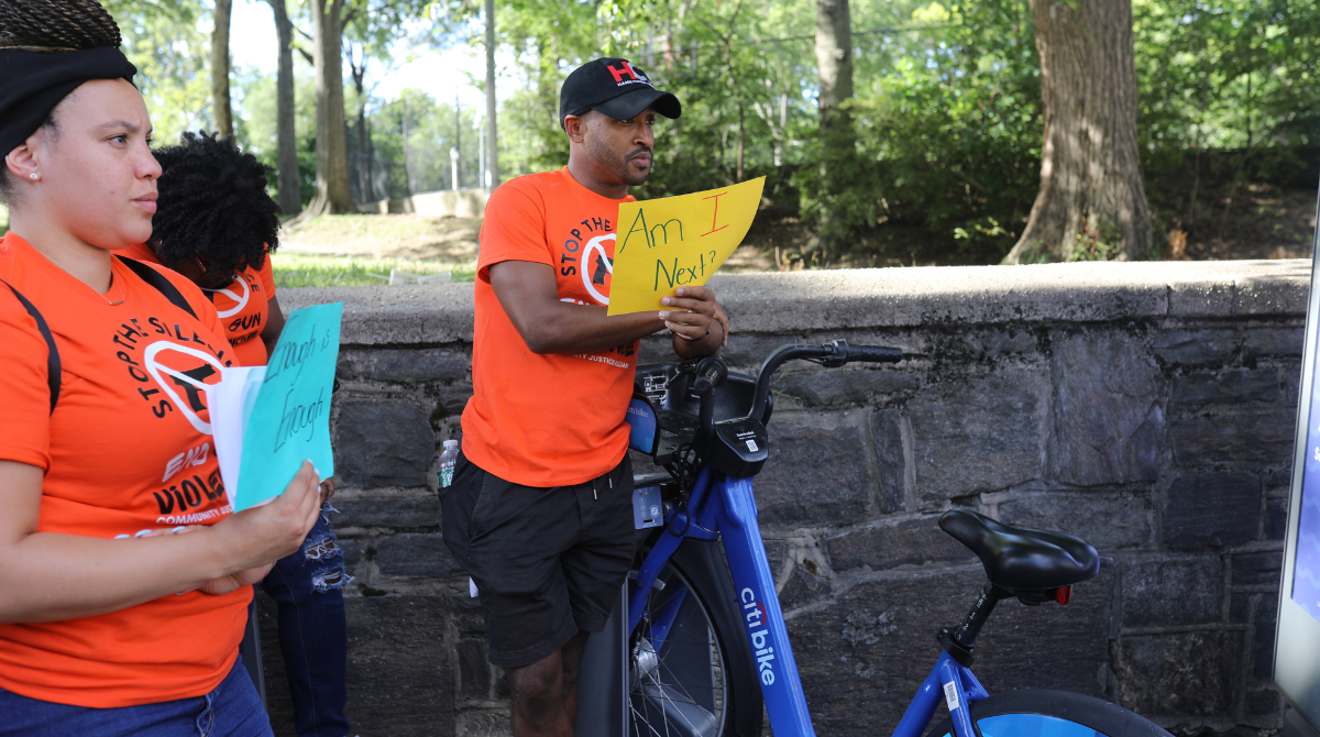 photo of a man holding a sign saying "Am I Next?"