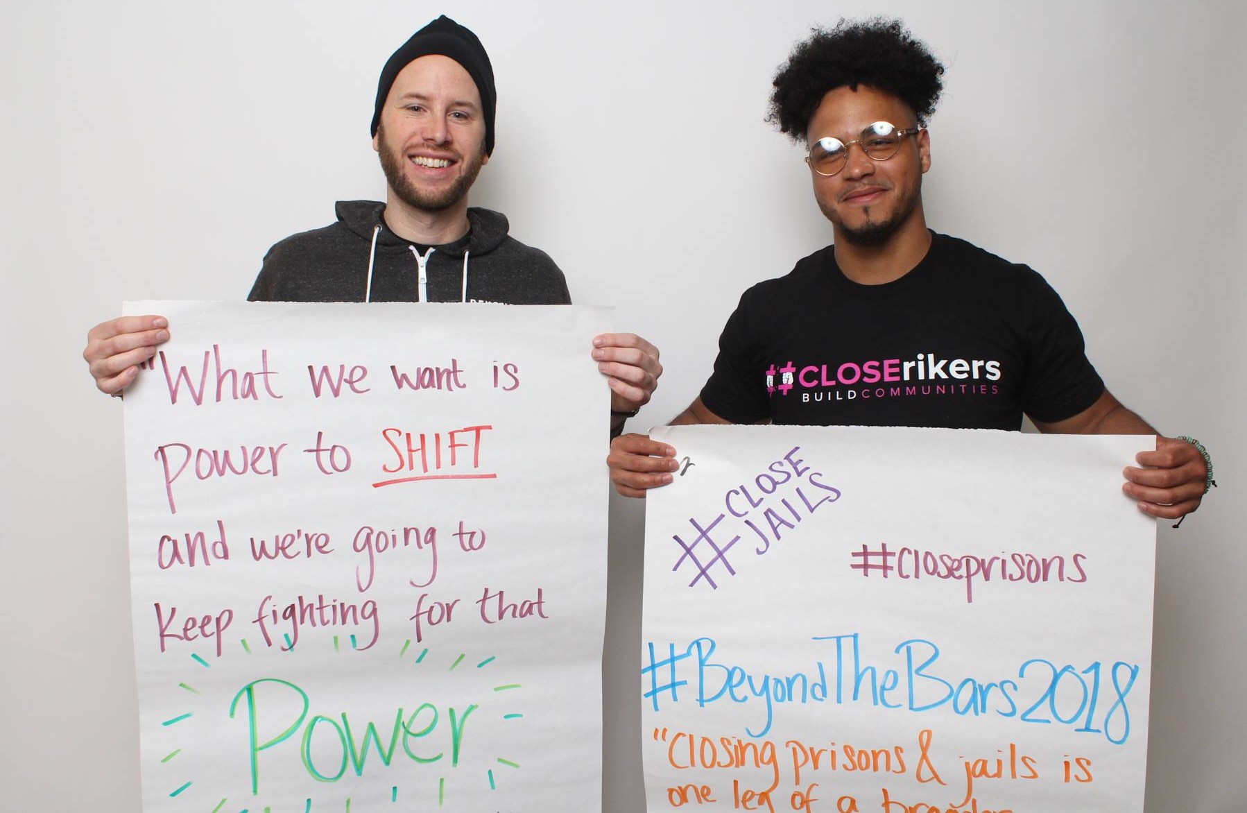 Two people holding signs advocating for the closure of jails and prisons